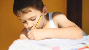 Chłopiec odrabia lekcje, pisząc lewą ręką