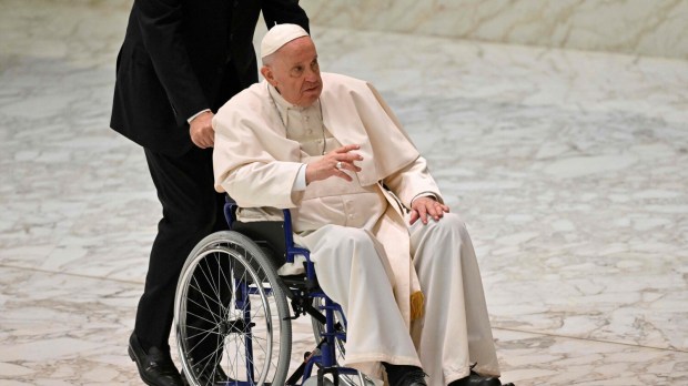 papież Franciszek jedzie na wózku inwalidzkim podczas audiencji w auli Pawła VI w Watykanie