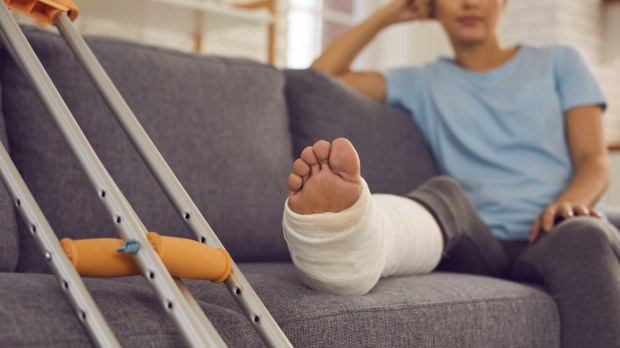 kobieta ze złamaną nogą siedzi na kanapie w salonie