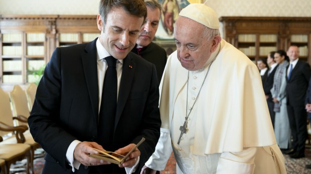 prezydent Francji Emmanuel Macron ogląda książkę, którą przywiózł jako prezent dla papieża