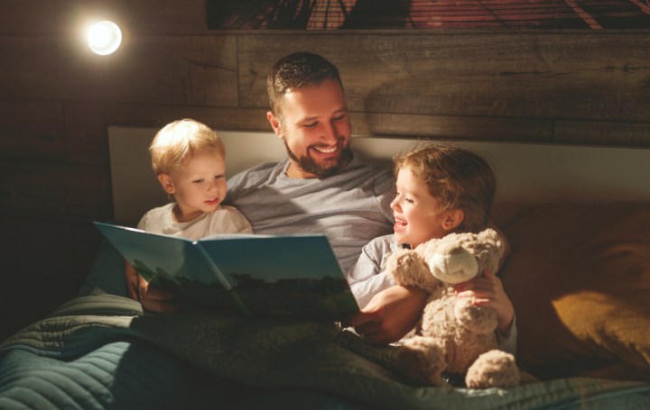 ojciec czyta wspólnie z dziećmi bajki na dobranoc