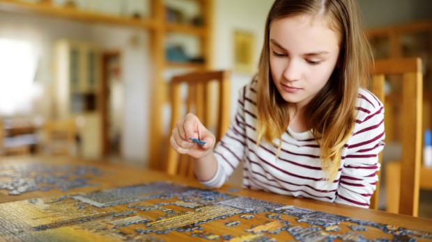 dziewczyna ćwiczy cierpliwość, układając puzzle