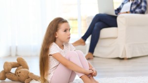 dziewczynka czuje się samotna i siedzi na dywanie gdy jej mama rozmawia przez telefon