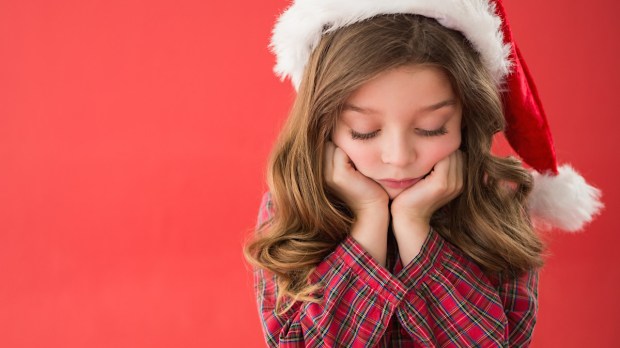 dziewczynka w czerwonej czapce smuci się na myśl o tym, że może nie otrzymać prezentu od świętego Mikołaja