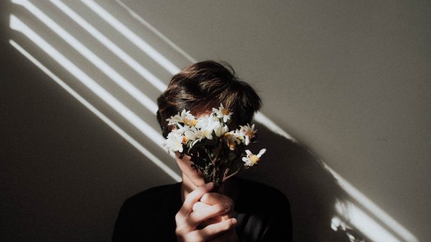 a person is holding a bouquet of white flowers covering his face with them