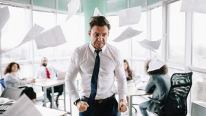 Wściekły menadżer rzuca papierami w biurze na oczach współpracowników
