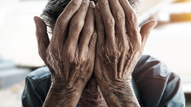Starszy człowiek zakrywa swoją twarz dłońmi